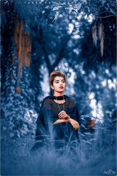 a woman is standing in the woods with her hands clasped to her chest and looking up