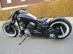 a black and white motorcycle parked in front of a brown building next to a bush