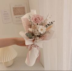 a person is holding a bouquet of flowers in their left hand, with the other hand on the wall behind them