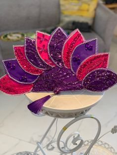 a purple, red and pink headpiece sitting on top of a white table next to a gray couch