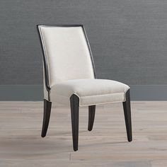 a white and black dining chair sitting on top of a hard wood floor next to a gray wall