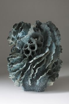 a vase that has some kind of thing on it's head in front of a gray background