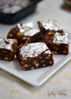 some brownies are on a white plate with silver flecks and powdered sugar