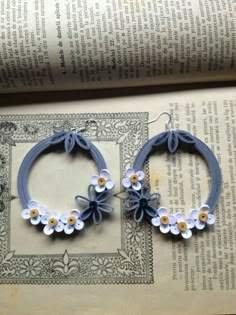 two pairs of blue and white flower hoop earrings sitting on top of an open book