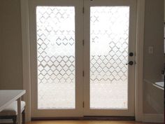 an empty room with two doors and a table in front of the glass door that is open