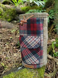 a plaid bag sitting on top of a moss covered ground