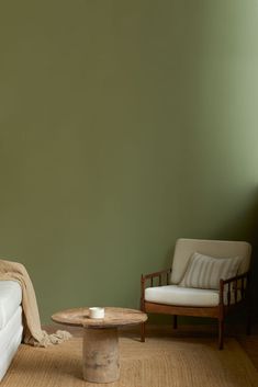 a living room with two chairs and a coffee table in front of a green wall