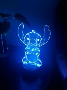 a blue light that looks like an elephant sitting on top of a table next to a potted plant