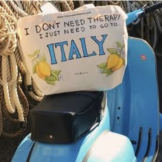 a blue scooter with a pillow on it's seat that says i don't need therapy, i just need to go to italy