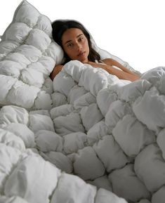 a woman is laying down in a bed made out of white blankets and pillows with her head resting on the pillow