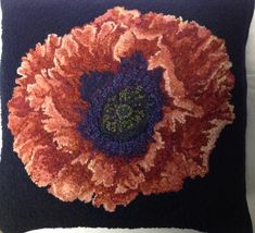 a black pillow with an orange flower on it