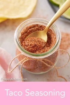 a jar filled with taco seasoning sitting on top of a table next to limes