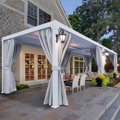 a patio covered in white curtains next to a house