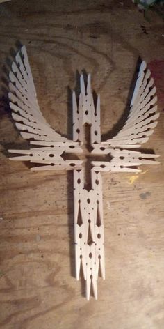 a cross made out of wood sitting on top of a wooden table with holes in it