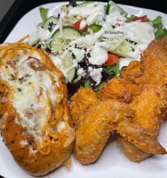 a white plate topped with fried chicken, salad and cheese covered breaded roll on top of it