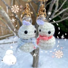 two small stuffed animals are hanging from key chains on a snow covered tree with snowflakes in the background