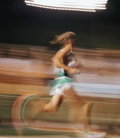 a blurry photo of a person running on a track with an audience in the background