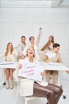 a woman holding a sign in front of her while other people sit at a table