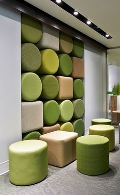 an office with green and yellow furniture in front of a wall covered in round cushions