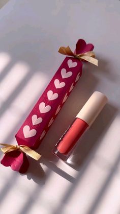 two lipstick tubes wrapped in pink paper with hearts on them