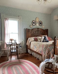 a bedroom with a bed, rocking chair, table and rug on the hardwood floor