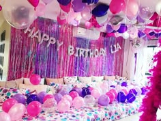 balloons and streamers are hanging from the ceiling in this birthday party room with pink, purple, and blue decor