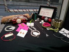 a table topped with lots of jewelry and christmas ornaments next to a sign that says happy holidays