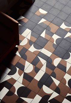 a tiled floor with black and white designs on it's sides, next to a chair