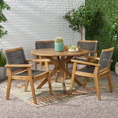 a wooden table with chairs around it in front of a brick wall and potted plant