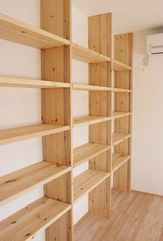 empty wooden shelves in a room with hard wood flooring and white walls, all lined up against the wall