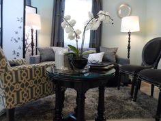 a living room filled with furniture and flowers on top of a glass topped coffee table