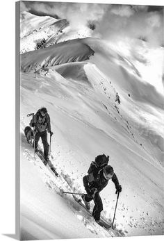 two people are skiing down a snowy mountain side with clouds in the sky behind them