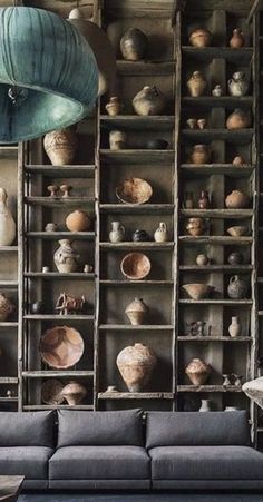 a living room filled with furniture and lots of vases on the wall behind it