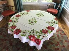 a white table with red poinsettis on it in front of a window