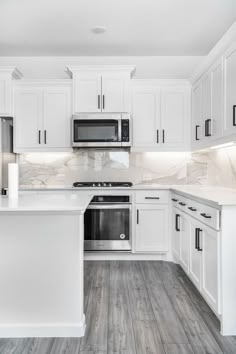 a kitchen with white cabinets and wood floors