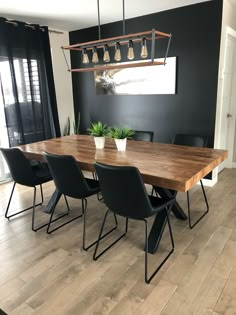 a dining room table with black chairs and a potted plant