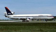 a delta airlines plane on the tarmac with grass and trees in the foreground