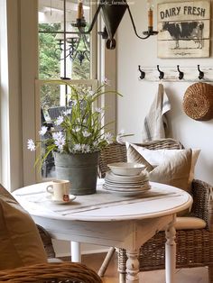 a dining room table with plates and cups on it in front of a large window