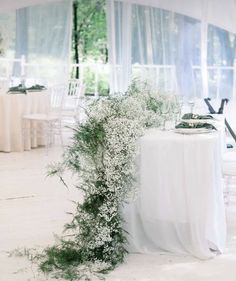 the table is set up with white linens and greenery for an outdoor function