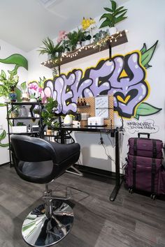 a chair in front of a wall with graffiti on it and plants hanging from the ceiling