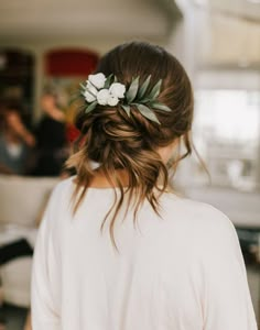 a woman with a flower in her hair wearing a white shirt and flowers in her hair