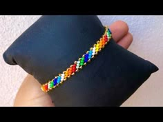 a person holding a black pillow with a colorful beaded bracelet on it