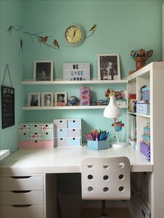 a white desk topped with lots of drawers next to a shelf filled with pictures and other items