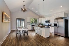 a large kitchen with white cabinets and wood flooring is pictured in this image, there are lights on the ceiling