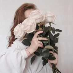 a woman with long hair holding flowers in front of her face