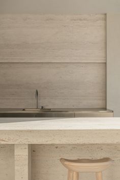 a kitchen counter with two stools next to it and a sink in the background