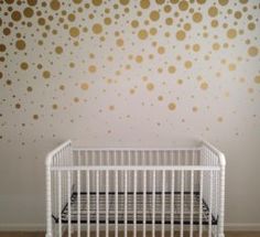 a white crib in front of a wall with gold dots