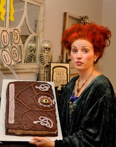 a woman with red hair holding up a cake