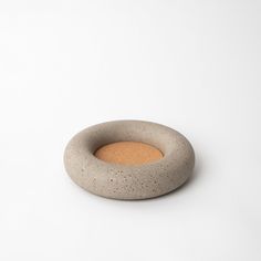 a small concrete bowl sitting on top of a white table next to an orange object