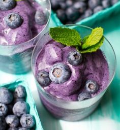 two glasses filled with blueberry smoothie and mint sprig on the side